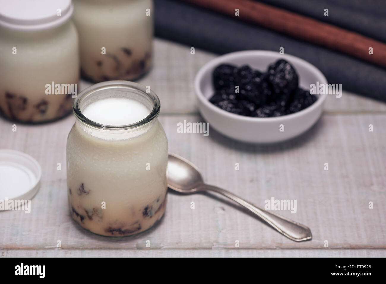 Leckere hausgemachte Joghurt mit gehacktem Pflaumen in Gläsern auf einem weißen Holztisch. Das Konzept der natürlichen und gesunden Frühstück Stockfoto
