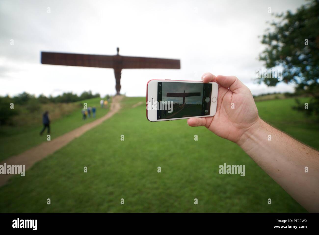 Tourist, der ein Foto von der Engel des Nordens Statue mit ihrem Telefon eine Person fotografieren der Engel des Nordens Skulptur in Tyne und Wear. Stockfoto