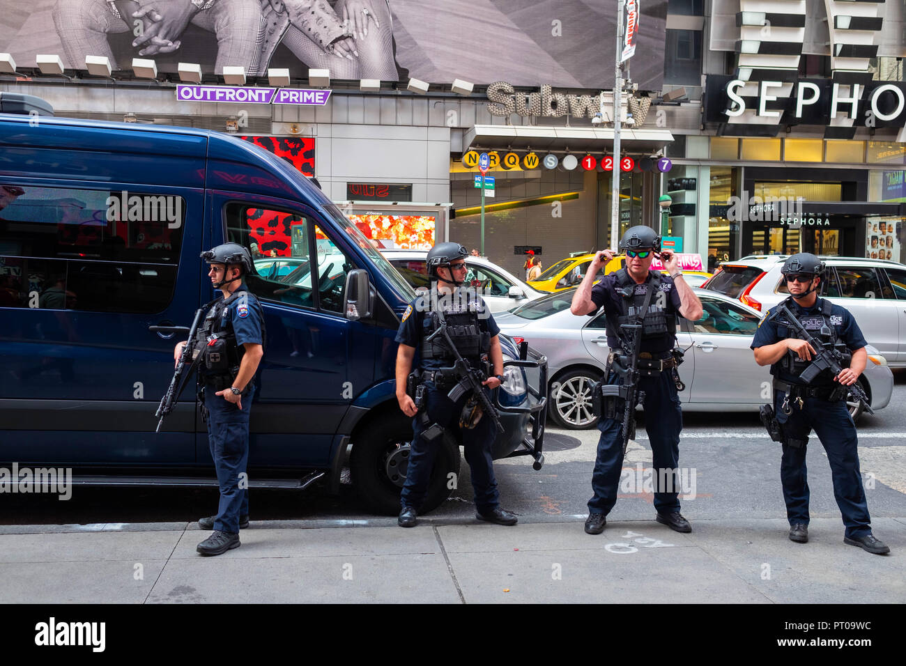 Vier schwer bewaffnete New Yorker Polizisten auf der Straße vor einer U-Bahn-Station am Times Square, Teil der Terrorabschreckung New Yorks Stockfoto