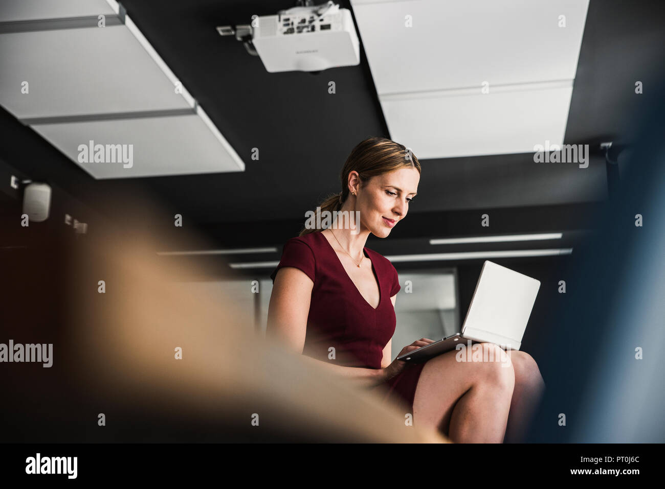 Im Büro Geschäftsfrau tragen Burgund Kleid mit Laptop Stockfoto