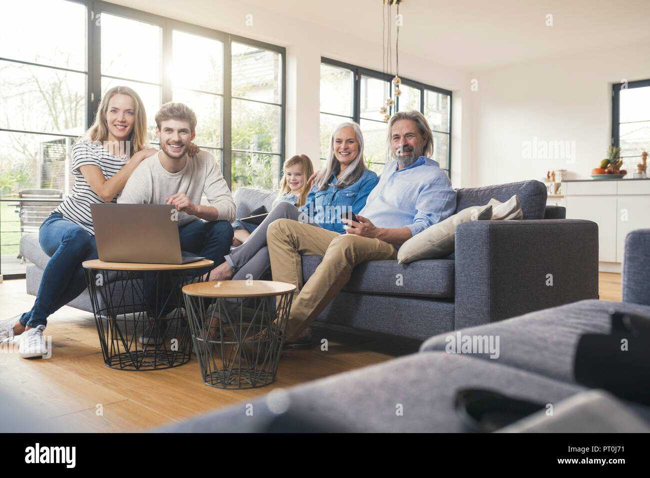 Erweiterte Familie sitzt auf der Couch, mit mobilen Geräten Stockfoto