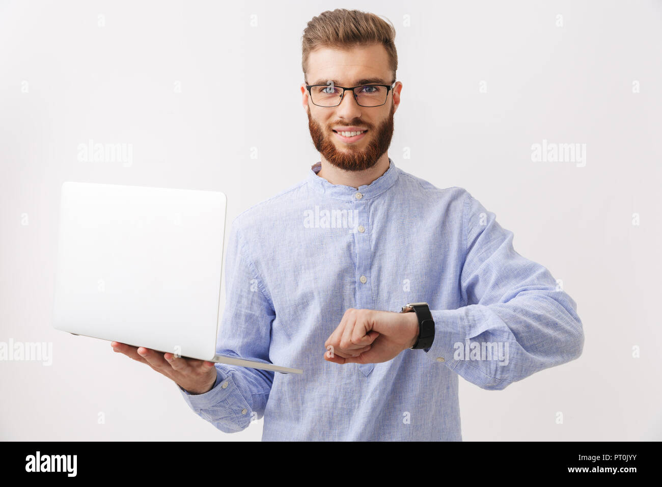 Porträt von einem aufgeregten Jungen bärtigen Mann in Brillen über Weiß isoliert, die hielten Laptop, Anzeigen Armbanduhr Stockfoto