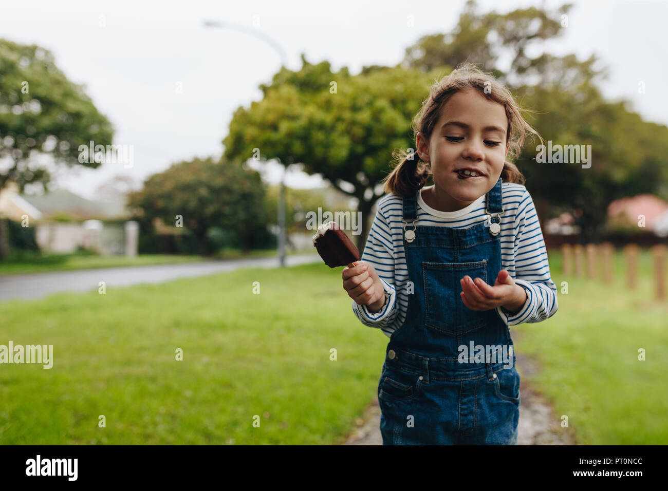 Portrait von niedlichen kleinen Mädchen Eis essen im Freien. Schöne junge Mädchen genießen eine Schokolade, Süßigkeiten, Eis. Stockfoto