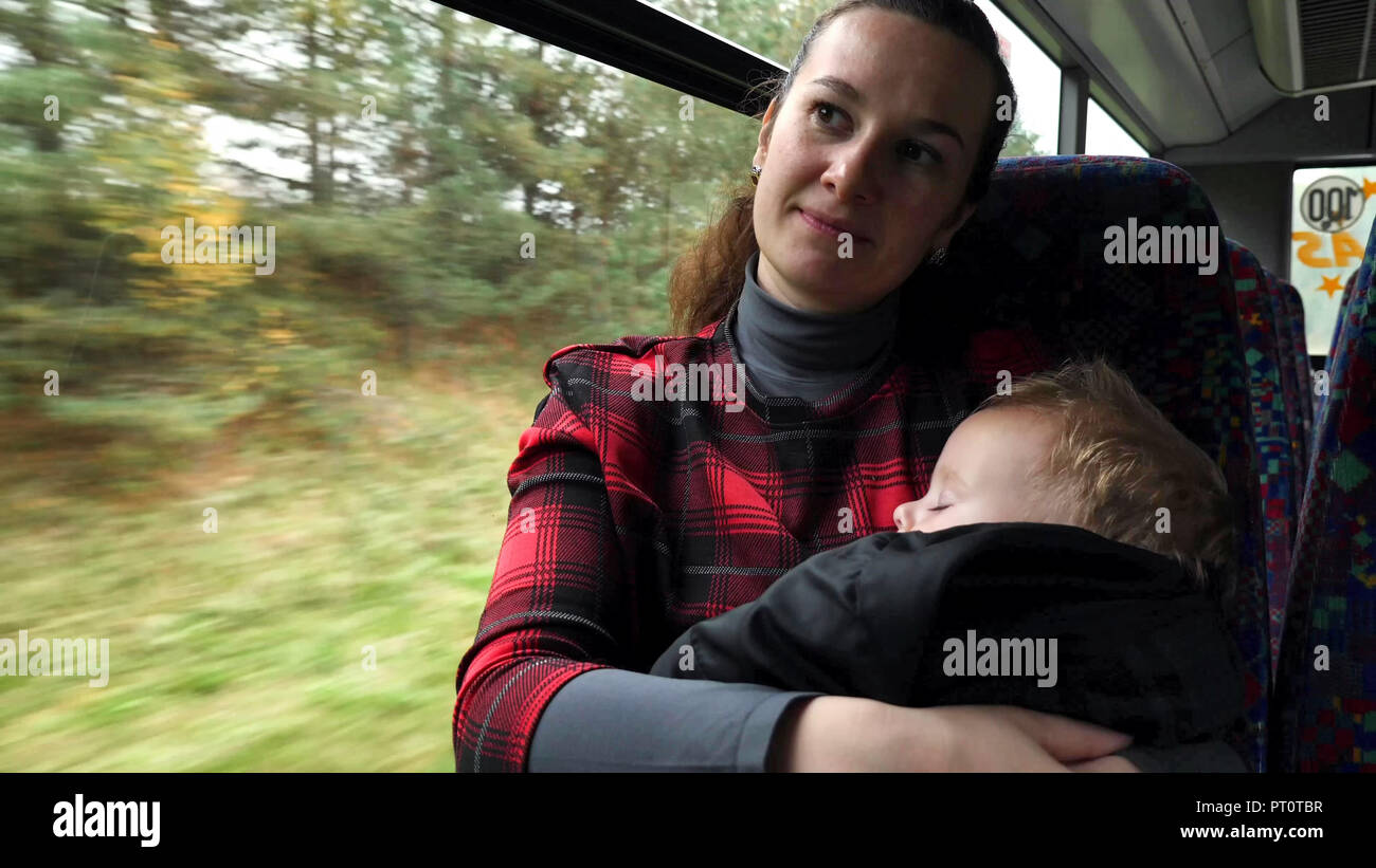 Die Mutter, die ihr Baby beim Pendeln mit Bus. Casual Schuß von Pendler alleinerziehende Mutter mit ihrem Baby Reisen mit dem Bus. Stockfoto