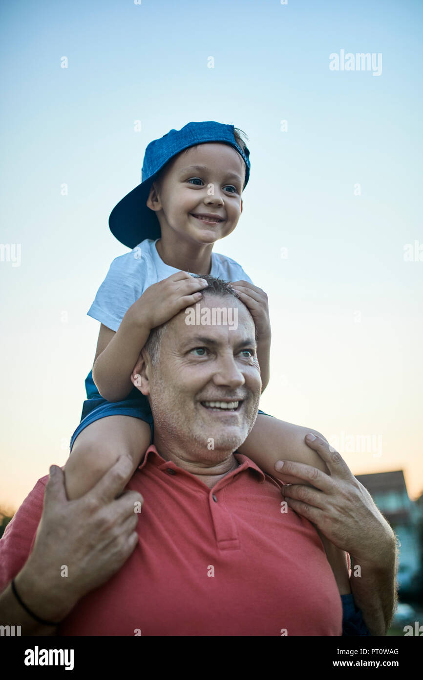 Portrait von glücklichen kleinen Jungen, auf den Schultern seines Großvaters Stockfoto