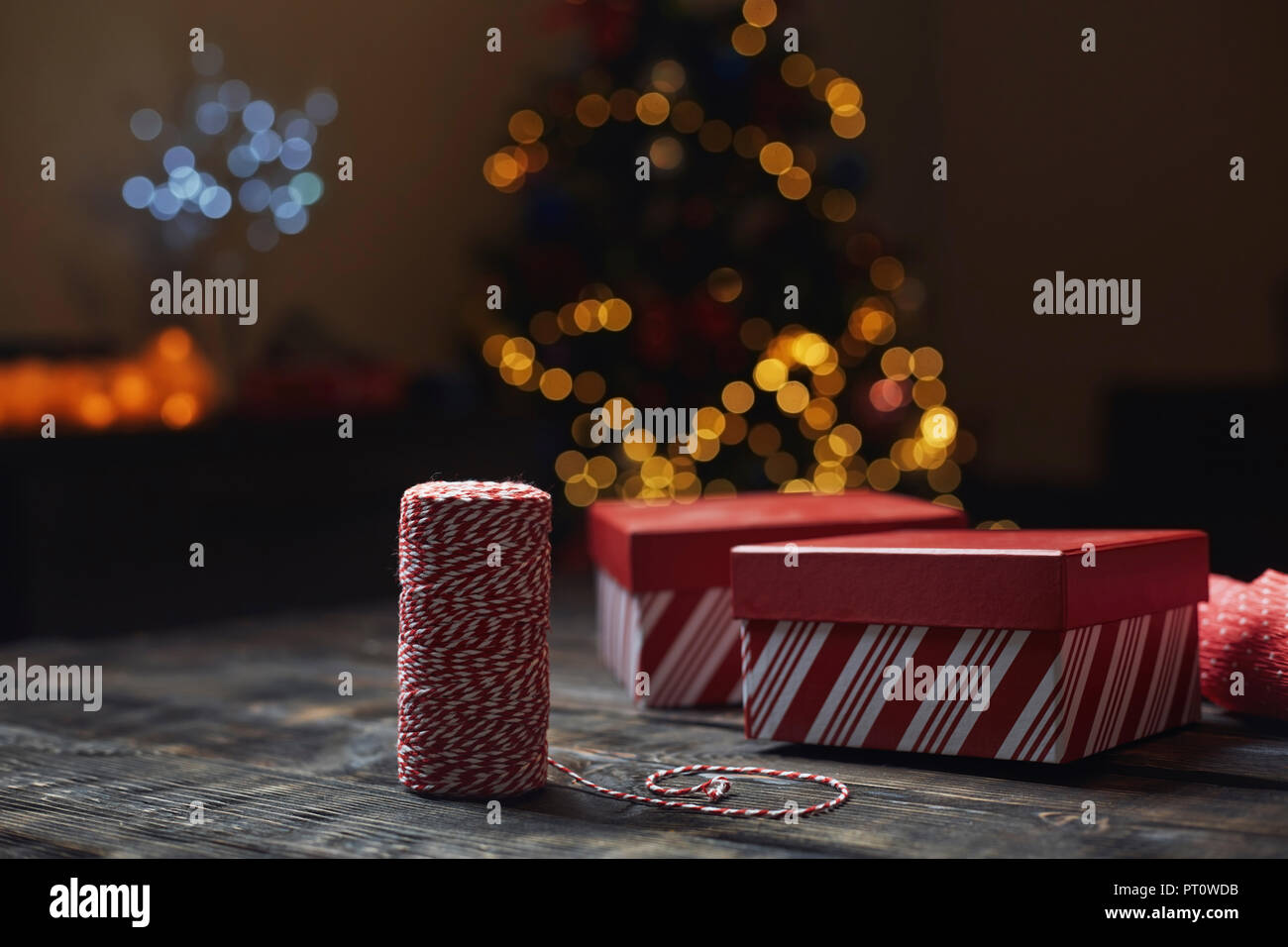 Rolle von rot-weißen packthread und geschenkboxen vor der beleuchteten Weihnachtsbaum Stockfoto