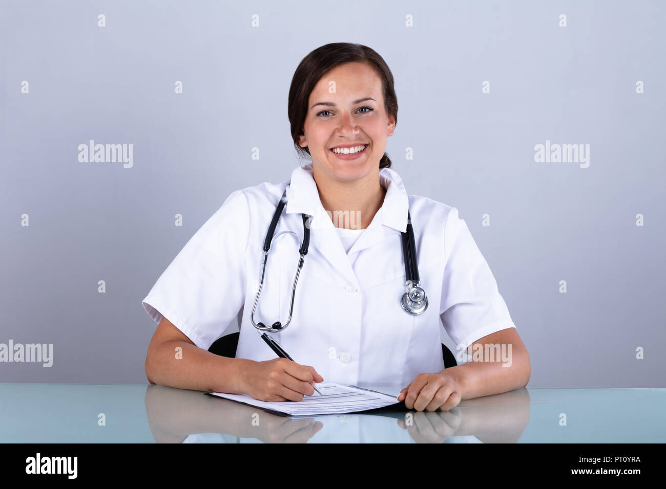 Portrait eines glücklichen jungen Frau Doktor mit Dokumenten in Klinik Stockfoto
