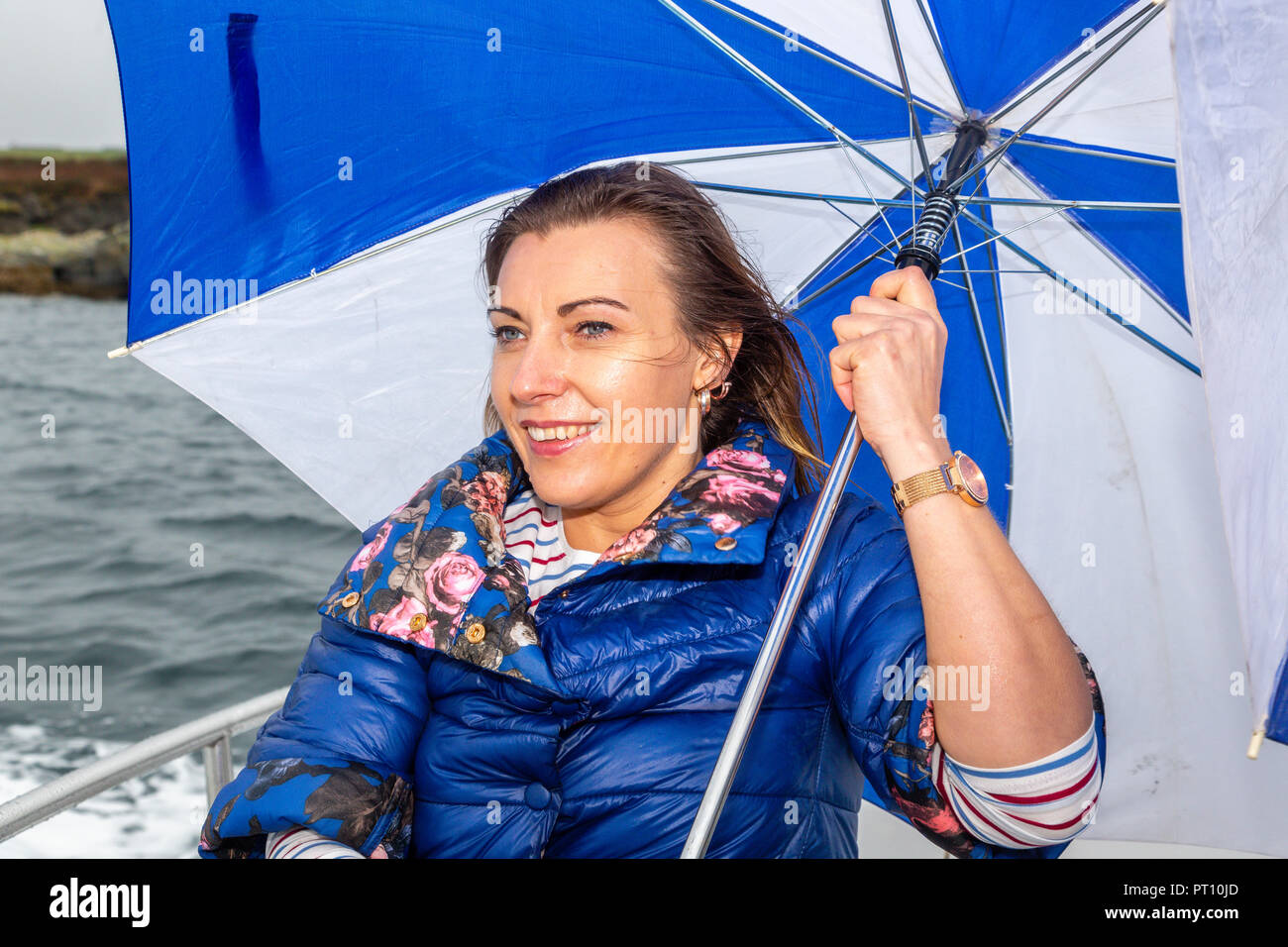 Blonde Frau auf einem Boot mit kaputten Regenschirm Stockfoto