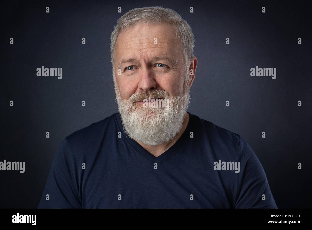 Glücklich 60 Jahre alten Mann mit grauem Bart posiert im Studio Stockfoto