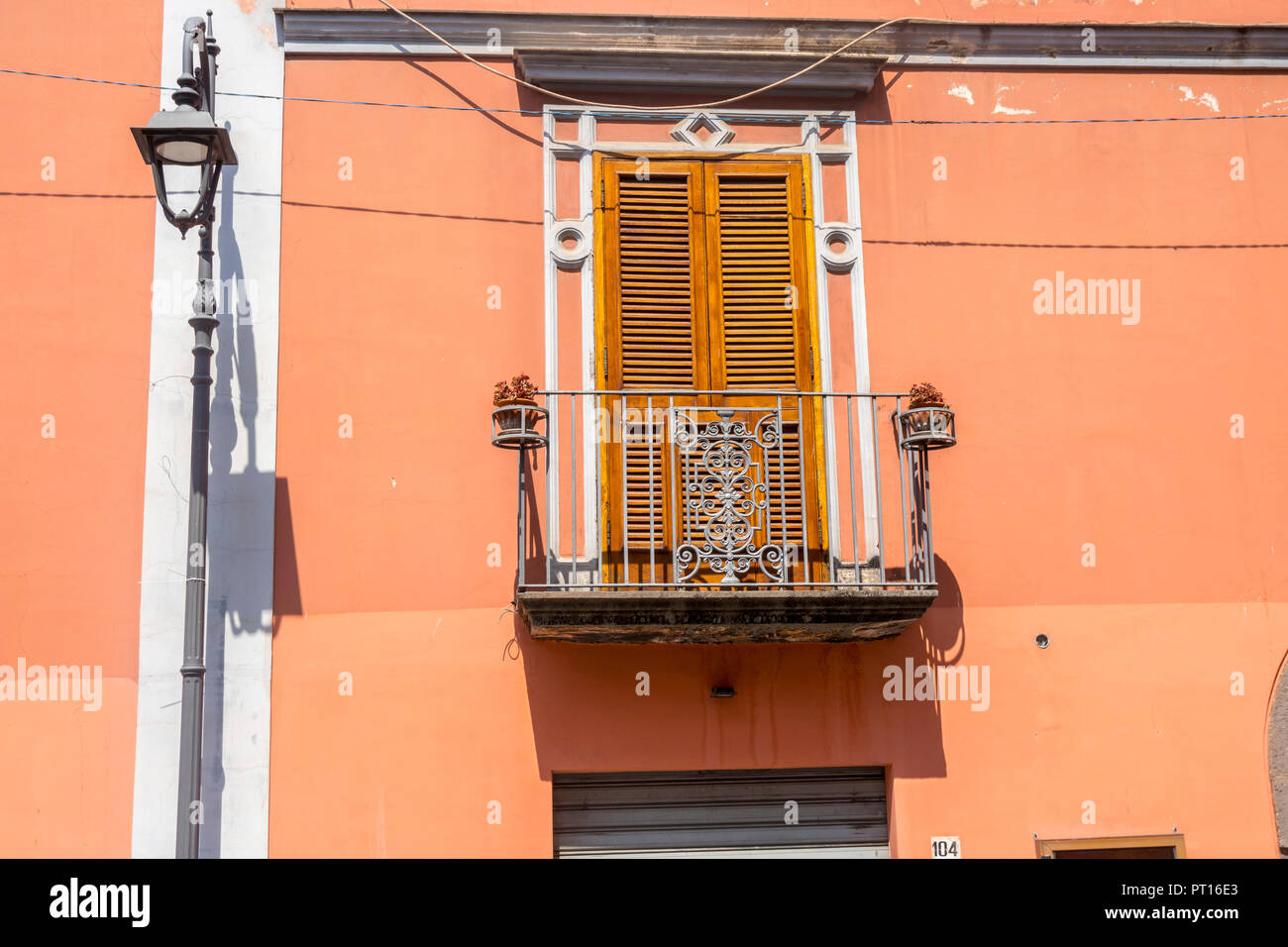Traditionelle italienische Tür mit Fensterläden, Metall balkon Italien, orange braun Wand über Shop, altmodisches Konzept, verzierte, Holz- Shutter Türen Stockfoto