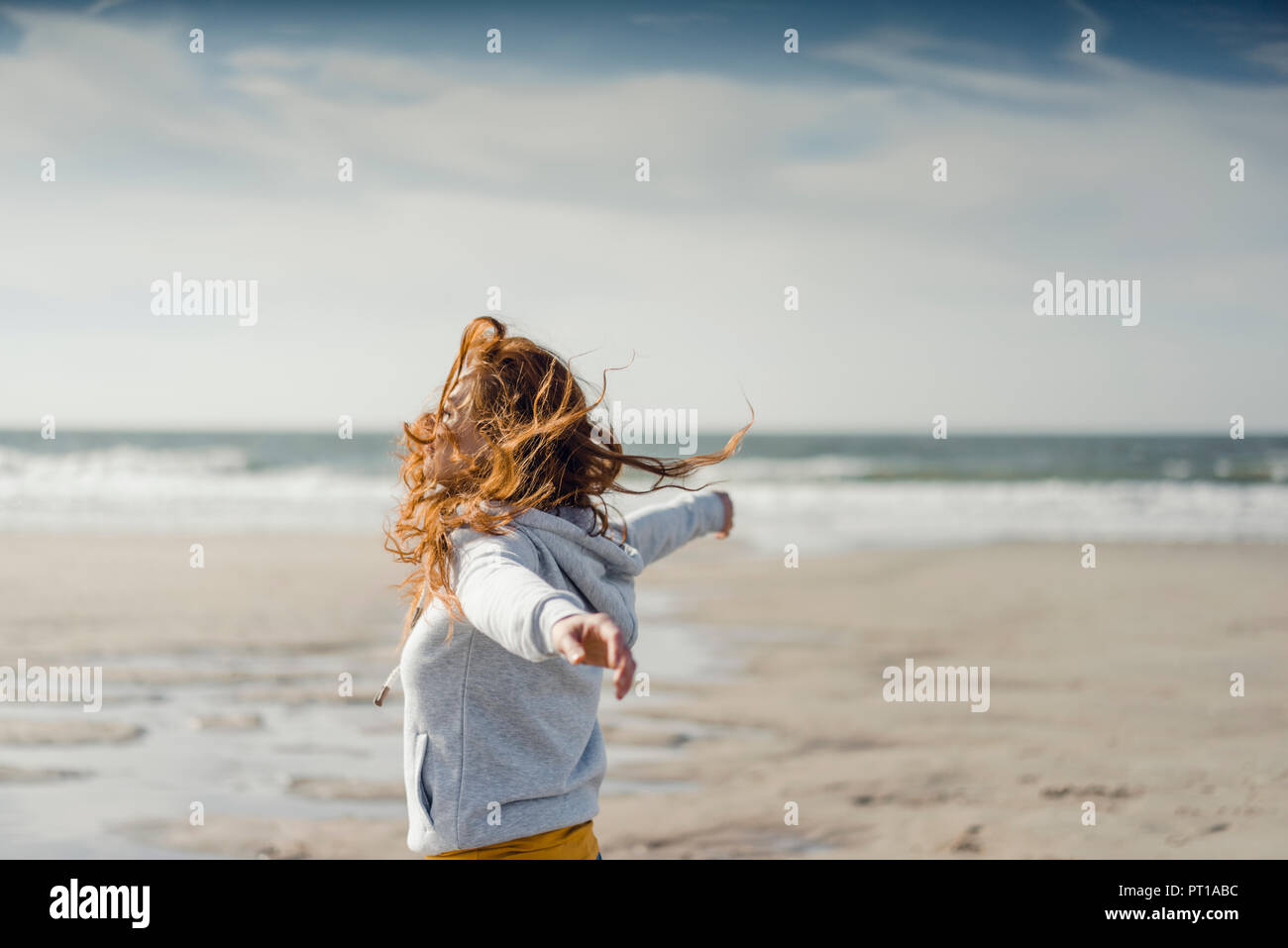 Rothaarige Frau am Strand entspannen, mit ausgestreckten Armen Stockfoto