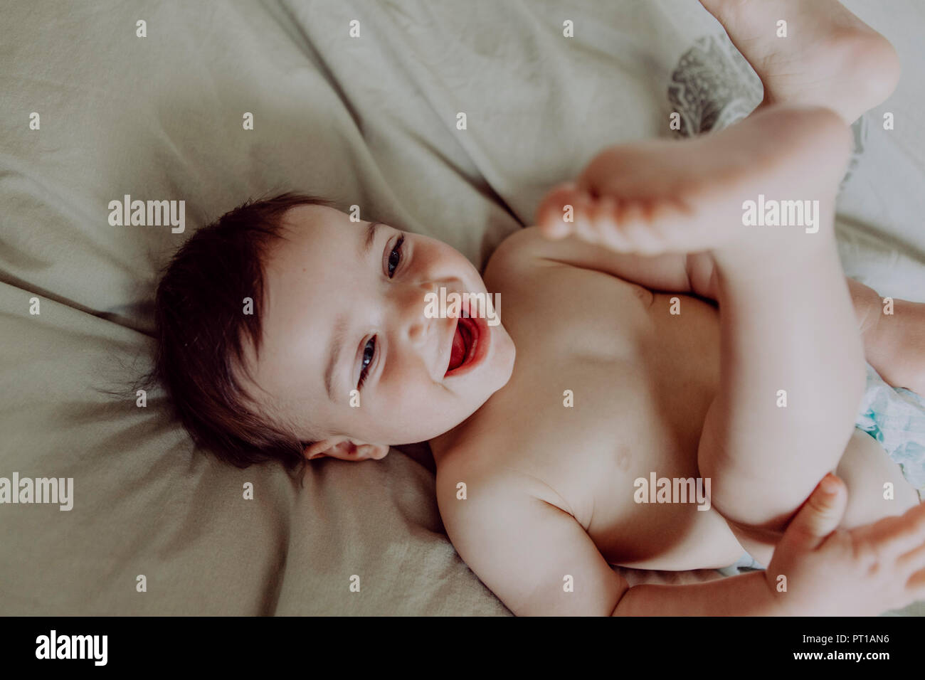 Happy Baby, liegend auf dem Bett, Lachen Stockfoto