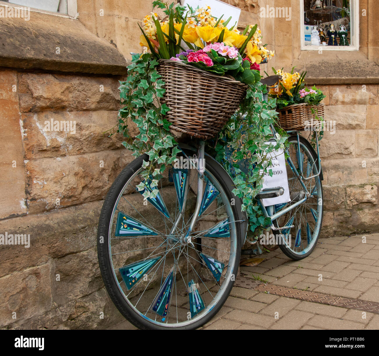 Altmodische Fahrrad mit Blume-Korb gefüllt und nachgestellte Ivy. Die Räder haben sprach Dekorationen aus mundgeblasenem Glas Dreiecke. Stockfoto