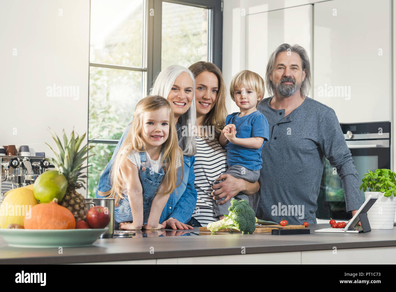 Großeltern mit Enkelkindern und ihre Mutter steht in der Küche Stockfoto