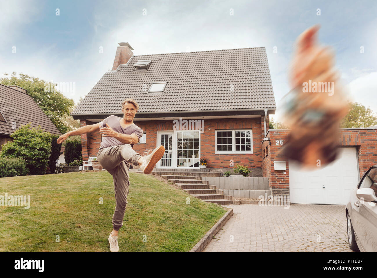 Reifer Mann entfernt kicking Gartenzwerg, vor seinem Haus Stockfoto