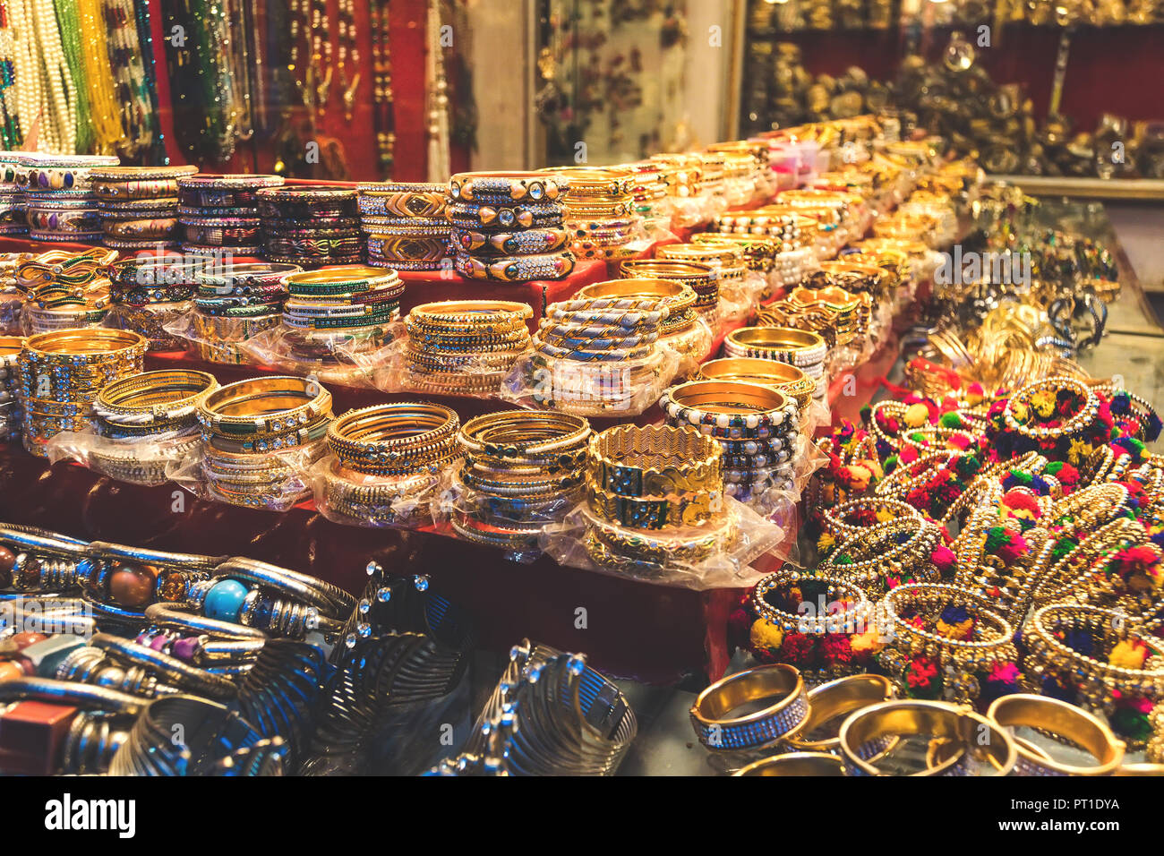 Traditionelle indische Armreifen und Armbänder an der Straße Markt in Udaipur, Rajasthan, Indien. Schmuck aus vergoldetem Metall mit bunten Steinen Stockfoto