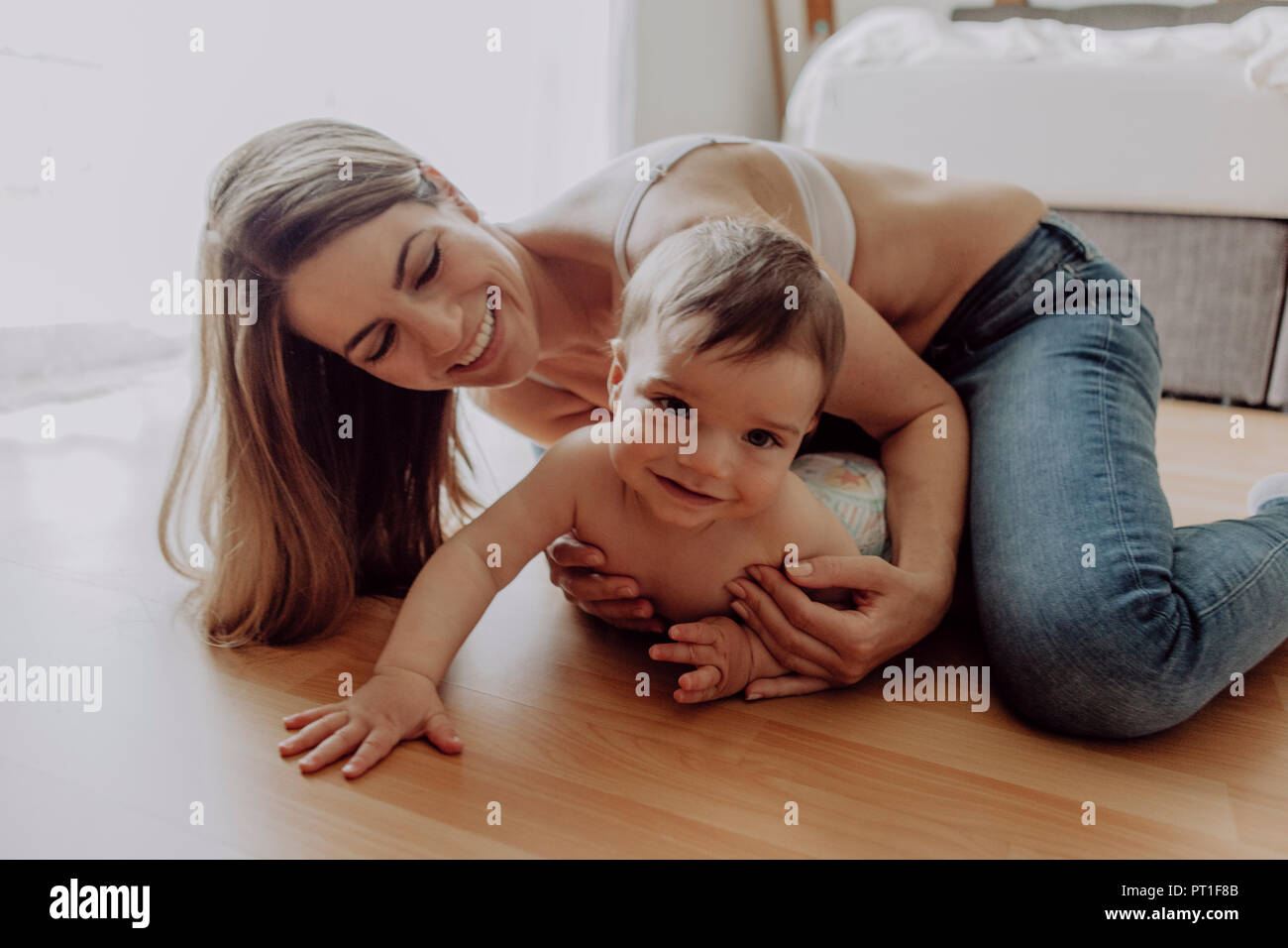 Mutter und Sohn spielen und krabbeln auf dem Boden Stockfoto