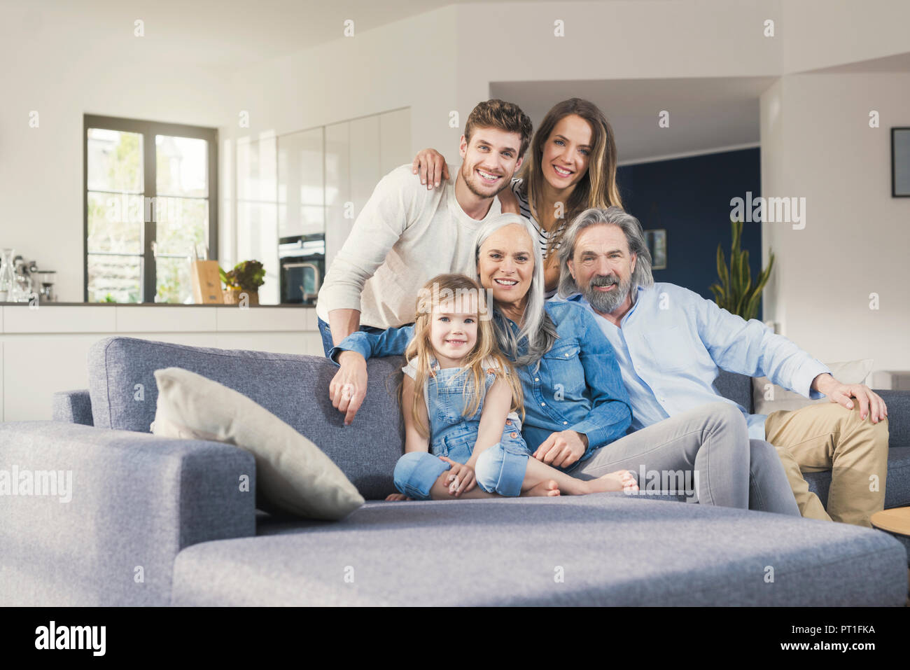 Erweiterte Familie sitzt auf der Couch, glücklich lächelnd Stockfoto