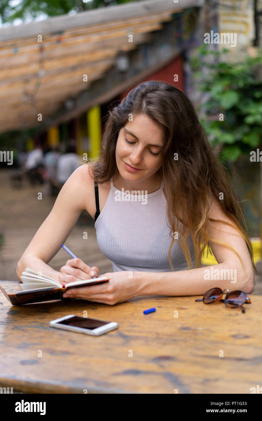 Junge Frau am Tisch sitzend Notizen Stockfoto