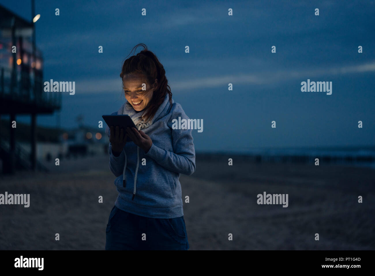 Frau mit digitalen Tablette am Strand bei Sonnenuntergang Stockfoto