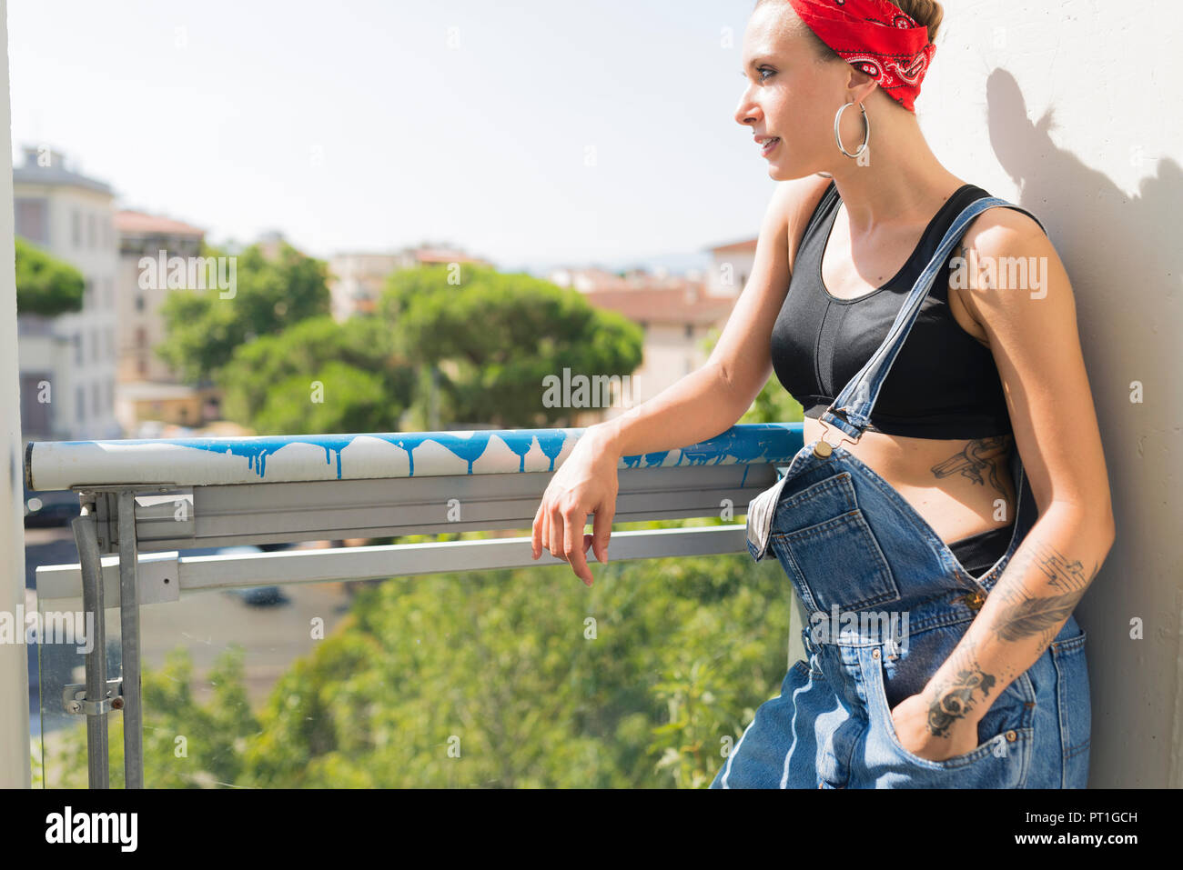 Tätowierte junge Frau stand auf dem Balkon mit Blick auf Abstand Stockfoto