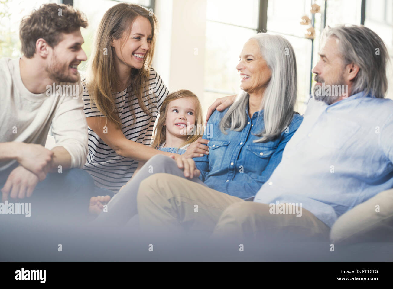 Erweiterte Familie sitzt auf der Couch, glücklich lächelnd Stockfoto