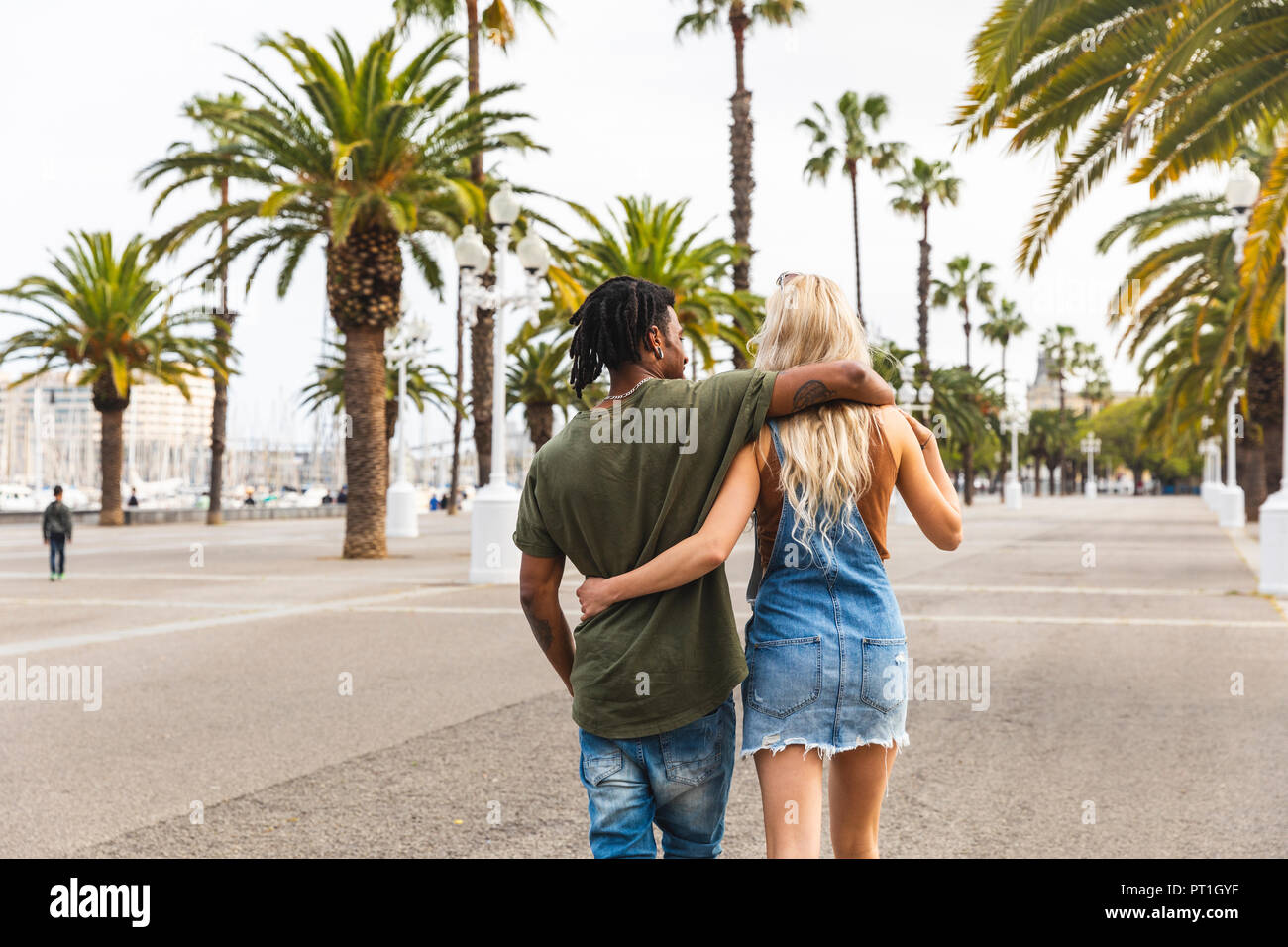Spanien, Barcelona, Rückansicht des multikulturellen junges Paar gehen Arm in Arm an der Promenade Stockfoto