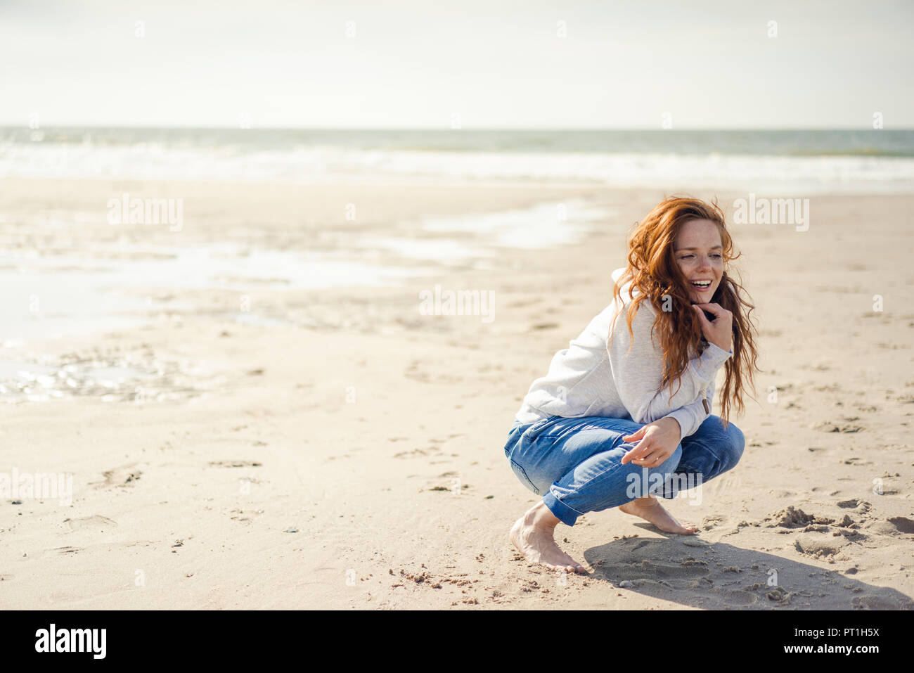 Rothaarige Frau am Strand entspannen, geduckt Stockfoto