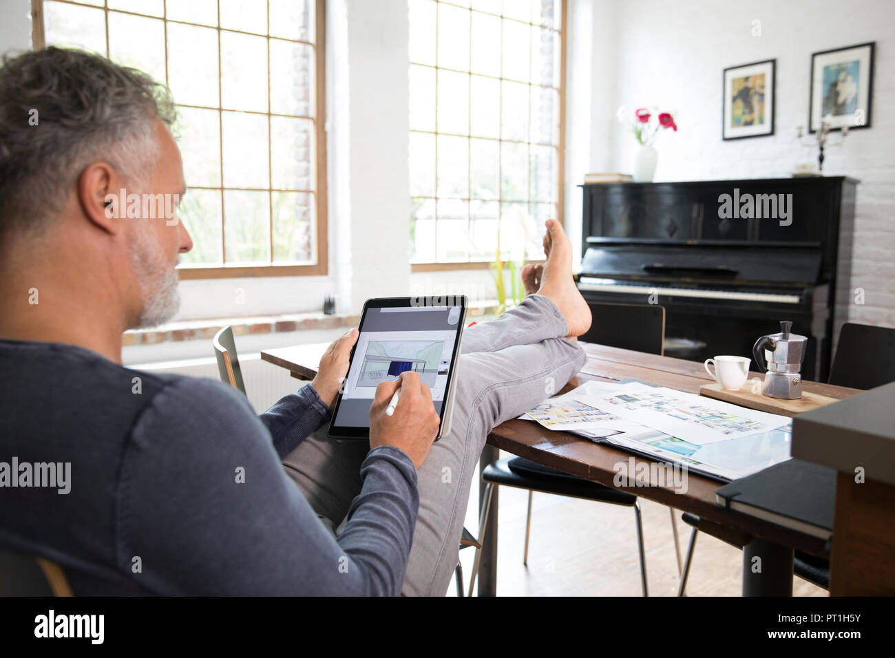 Reifer Mann laufen, das von seinem Home Office mit Füße hochlegen, auf Tablet Stockfoto