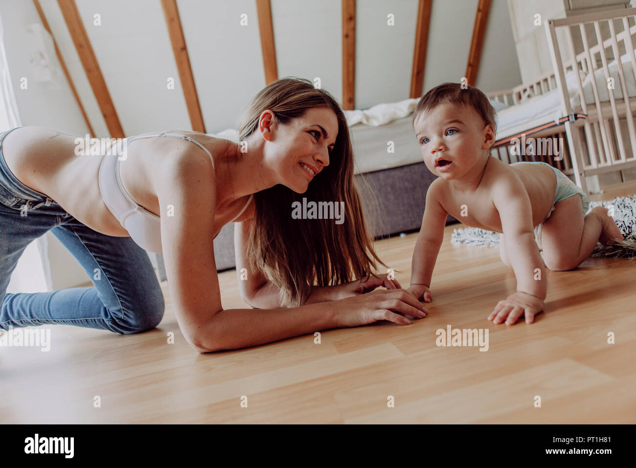 Mutter und Sohn spielen und krabbeln auf dem Boden Stockfoto