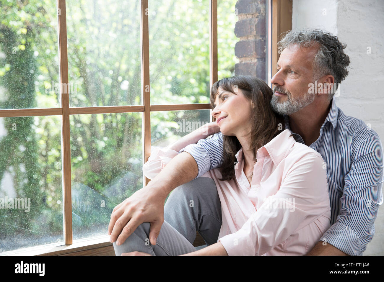 Reifes Paar sitzt auf der Fensterbank und schaut aus dem Fenster Stockfoto