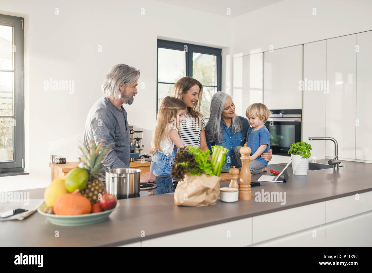 Großeltern mit Enkelkindern und ihre Mutter steht in der Küche Stockfoto