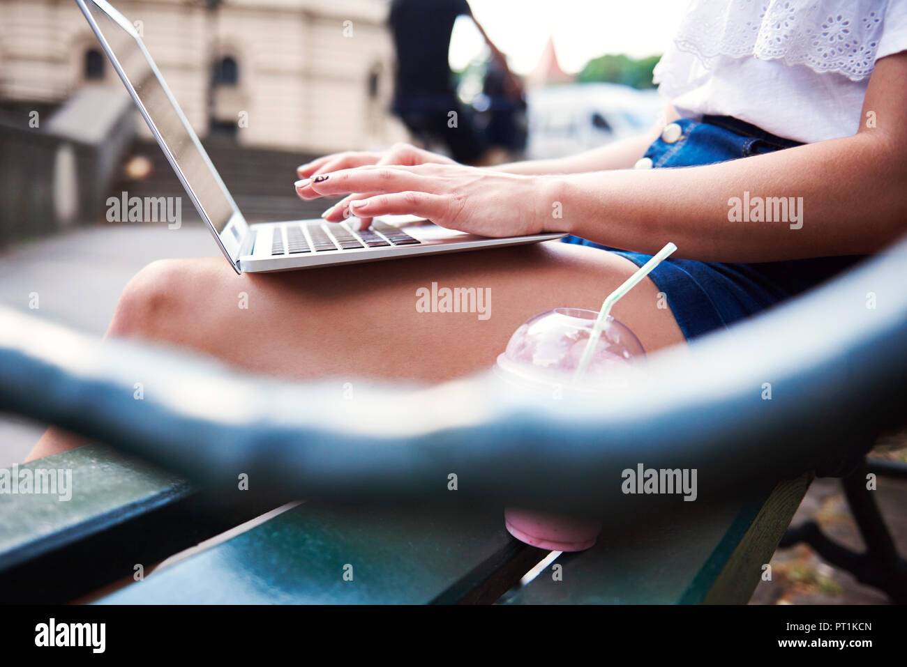 Junge Frau sitzt auf der Bank mit Laptop, Teilansicht Stockfoto