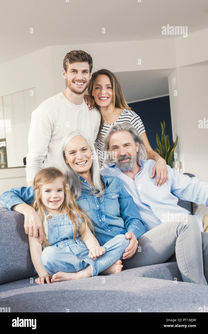 Erweiterte Familie sitzt auf der Couch, glücklich lächelnd Stockfoto