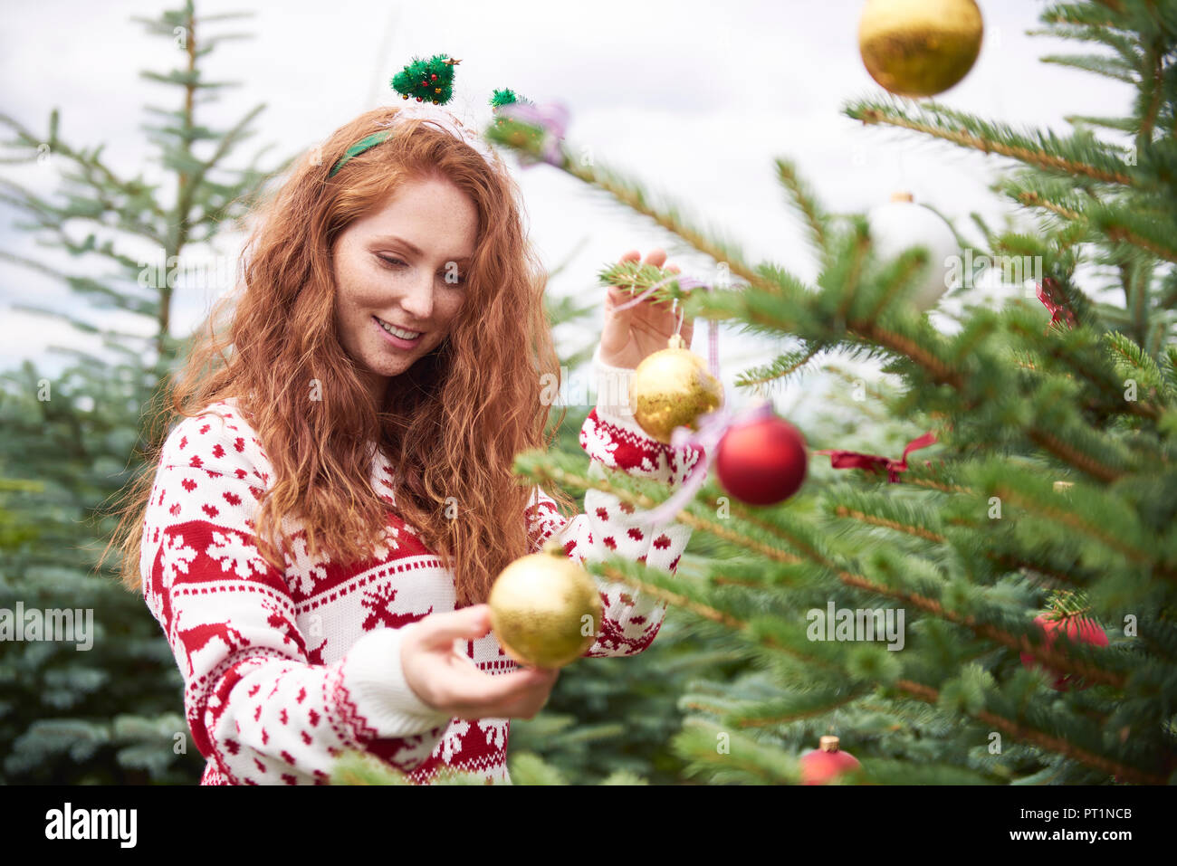 Porträt der rothaarige junge Frau schmücken Weihnachtsbaum im Freien Stockfoto