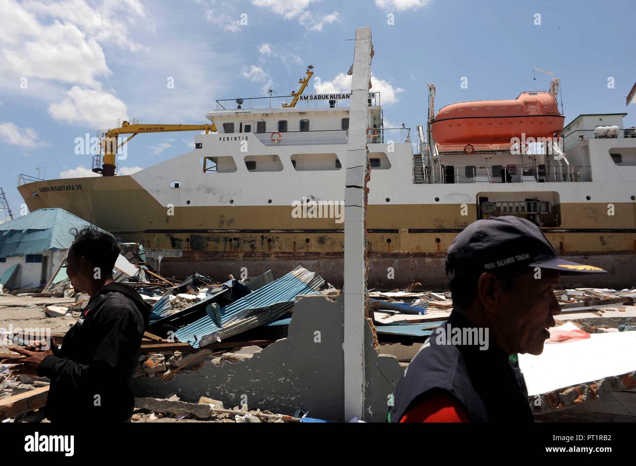 Donggala, Indonesien. 5. Okt, 2018. Die Bewohner stehen in der Nähe von einem gestrandeten Schiff in Donggala, Central Sulawesi, Indonesien, am Okt. 5, 2018. Die Zahl der Todesopfer in Indonesien mehrere Erdbeben und einer darauf folgenden Tsunami sprang auf 1.571, während der Suche und Rettung der Opfer erweitert wurde, die Disaster Management Agency am Freitag sagte. Credit: Agung Kuncahya B./Xinhua/Alamy leben Nachrichten Stockfoto