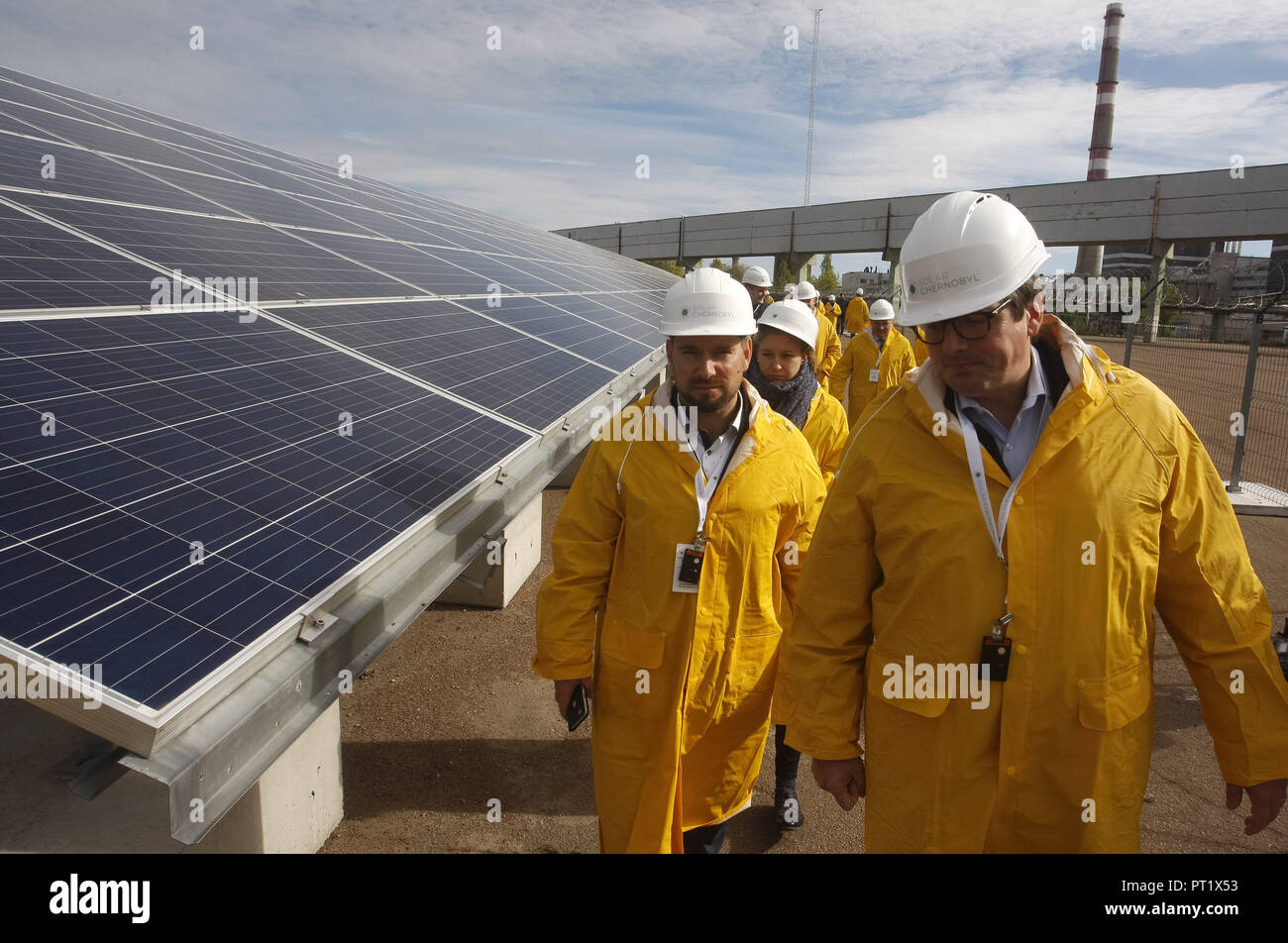 Kiew, Ukraine. 5. Okt, 2018. Besucher vorbei an Solarmodulen der ersten Solaranlage olar Tschernobyl" vor der neuen Schutzkonstruktion Bogen für den beschädigten Reaktor 4 des Kernkraftwerks von Tschernobyl entfernt, während eine Eröffnungsfeier in Tschernobyl. Credit: Serg Glovny/ZUMA Draht/Alamy leben Nachrichten Stockfoto