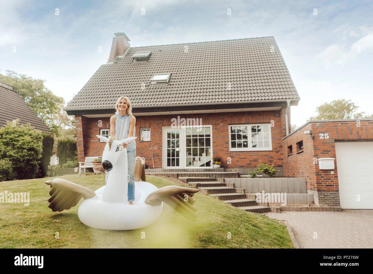 Portrait von lächelnden reife Frau mit aufblasbaren Pool Spielzeug im Garten von Ihrem Haus Stockfoto