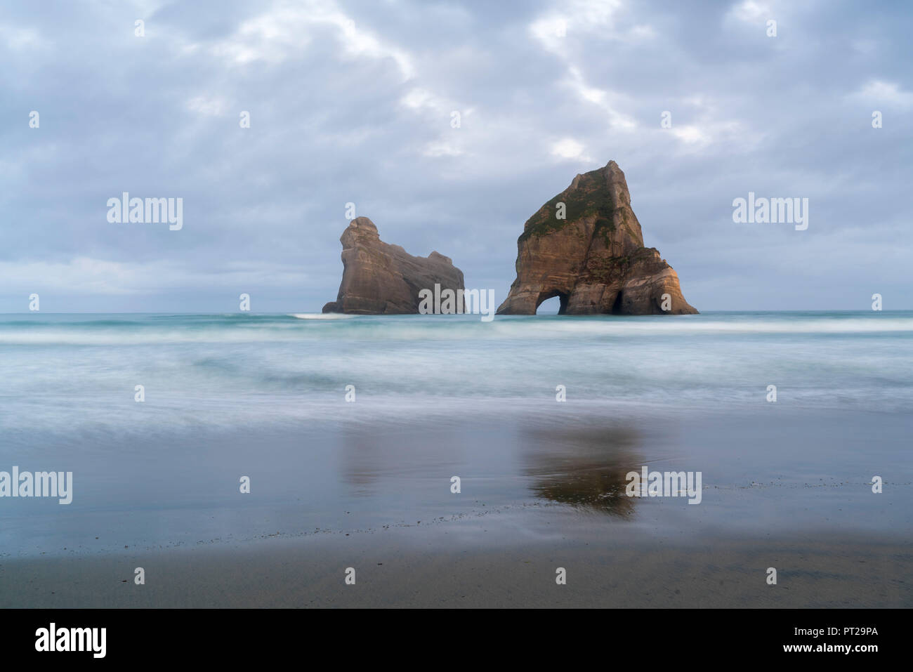 Moody Himmel über zwei der Torbogen Inseln, Wharariki Beach, Puponga, Tasman District, South Island, Neuseeland, Stockfoto