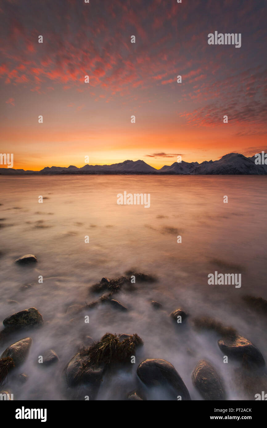 Die Wellen auf den Steinen am Strand brechen bei Sonnenuntergang, Nordmannvik, Kafjord, Lyngen Alpen, Troms, Norwegen, Lappland, Europa, Stockfoto