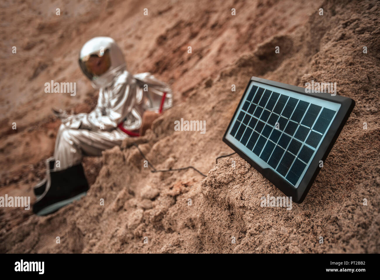 Spaceman sitzen auf namenlosen Planeten, Ladegerät mit Solarmodul Stockfoto