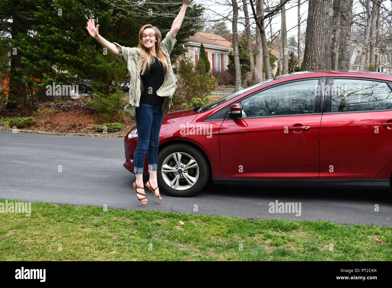 Gerne blonde Mädchen vor Freude hüpfend durch neues Auto Stockfoto