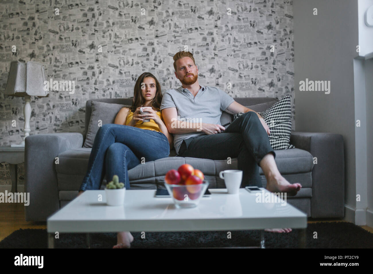 Junges Paar sitzt auf der Couch vor dem Fernseher Stockfoto