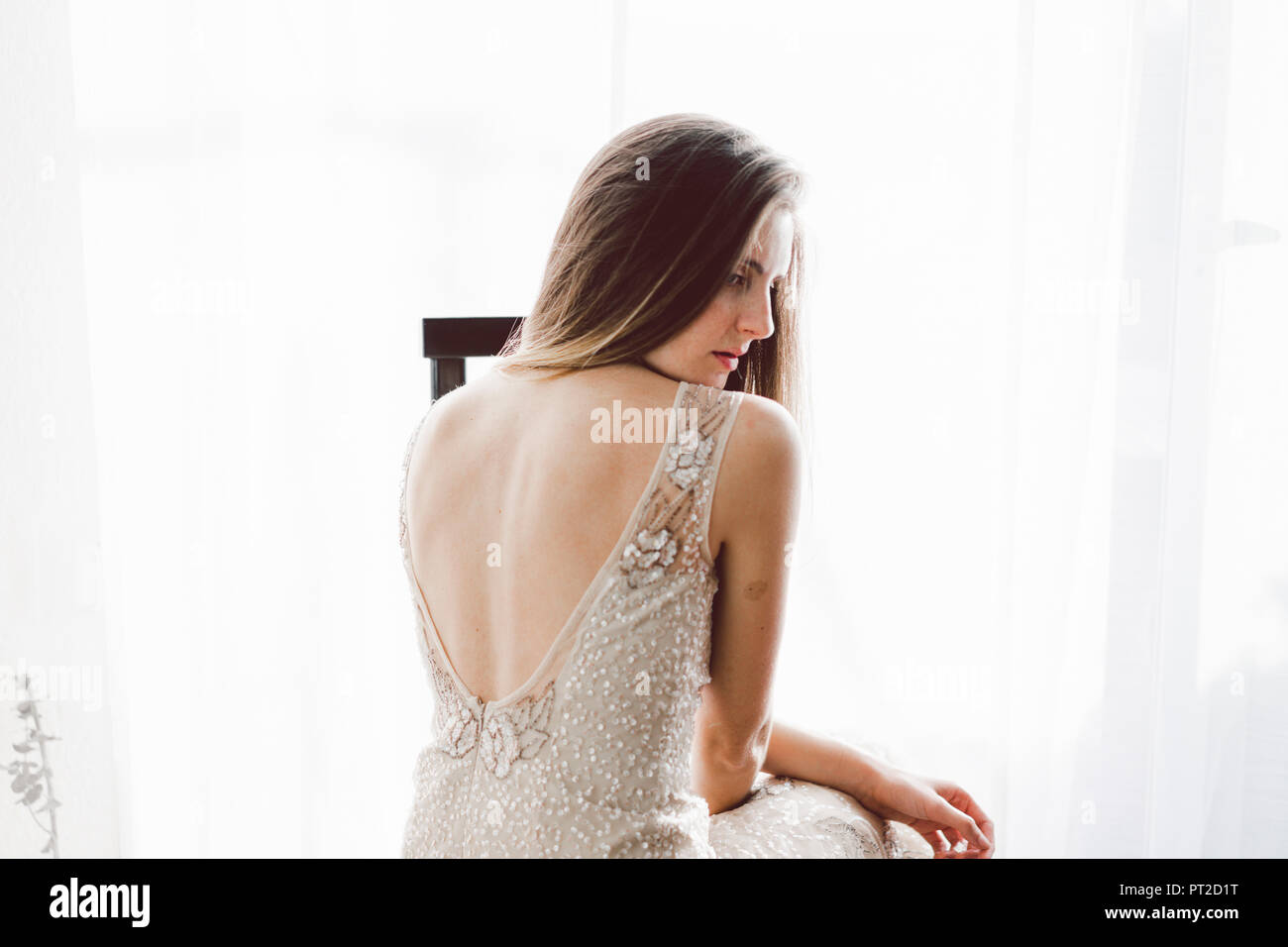Junge Frau trägt ein Brautkleid im Innenbereich Stockfoto