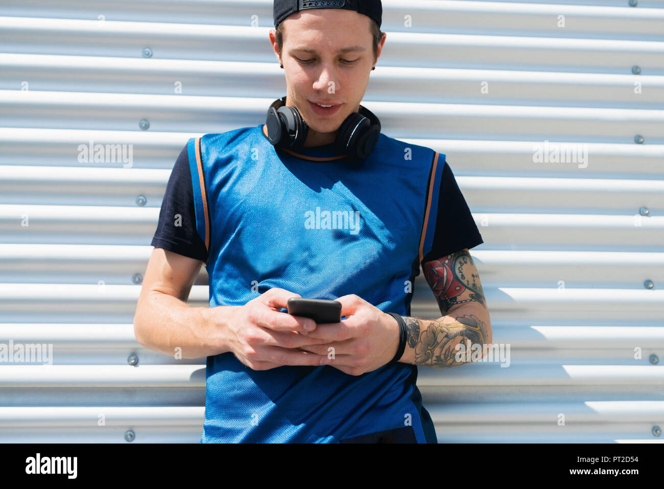 Tätowierten jungen Mann mit Kopfhörern bei Zelle Telefon Stockfoto