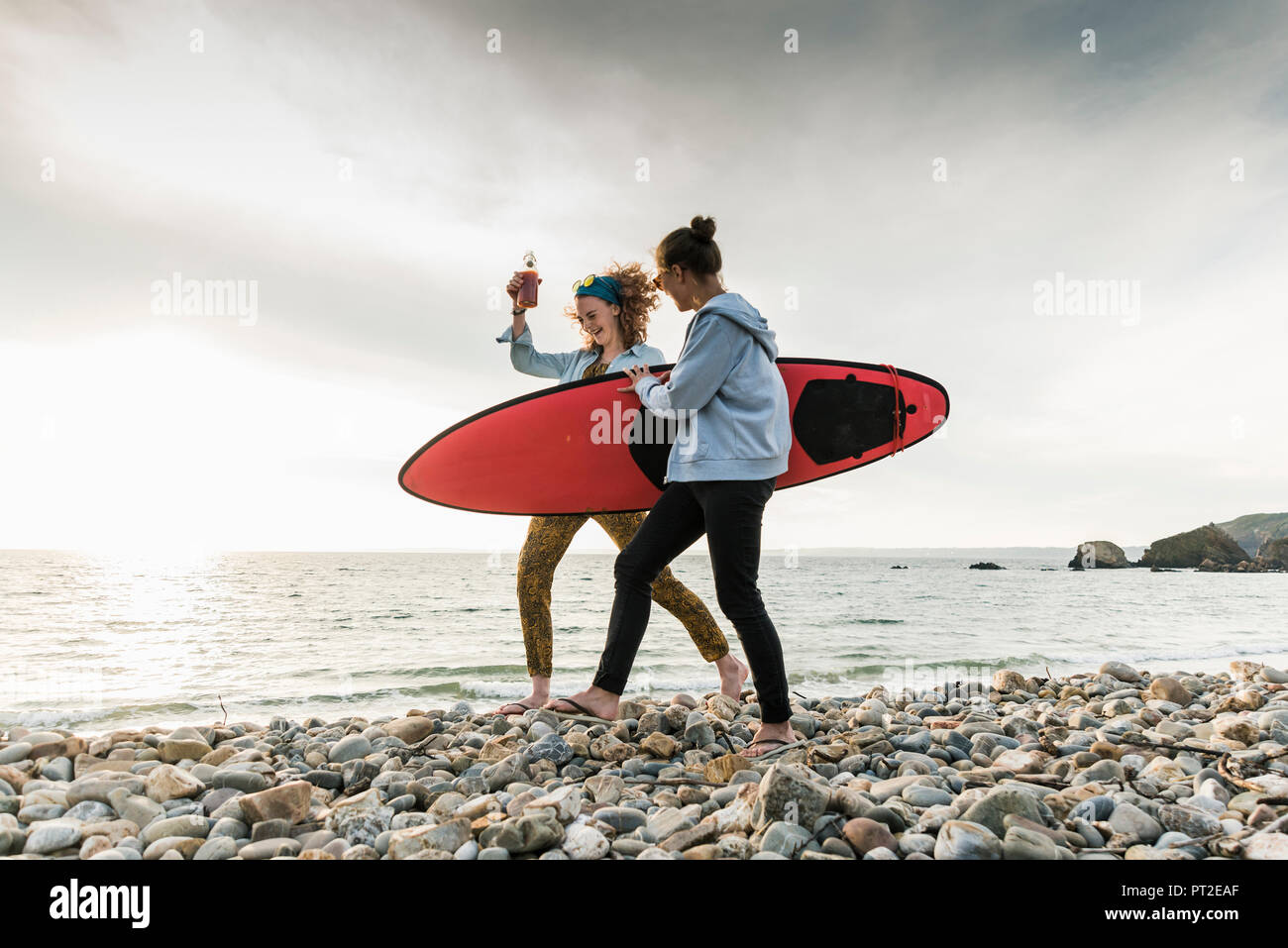 Gerne Freunde mit Surfbrett zu Fuß auf steinigem Strand Stockfoto