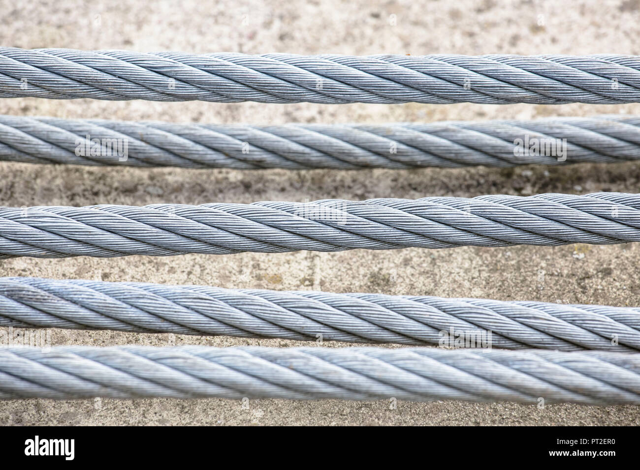 Kabel aus Stahl vor einem Betonklotz, Stockfoto