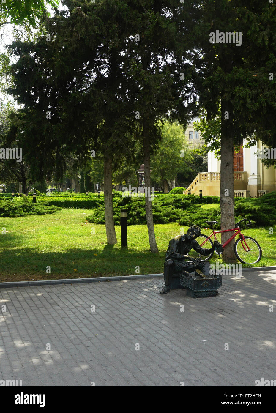 Sympathische Schuhputzmaschine/-service Opa Skulptur vor seinem Fahrrad in einem Park und wartet auf seine nächste Client. Stockfoto