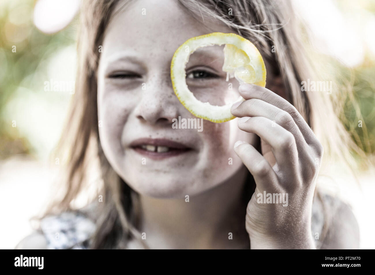 Mädchen schaut durch Zitronenscheibe Stockfoto