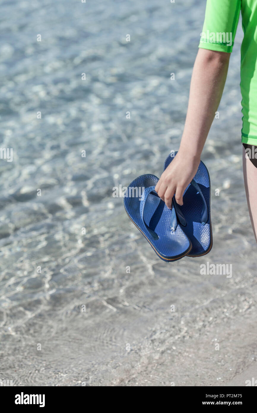 Mädchen mit Flip-flops in die Hand vor das kristallklare Wasser am Strand von Palombaggia, Korsika Stockfoto